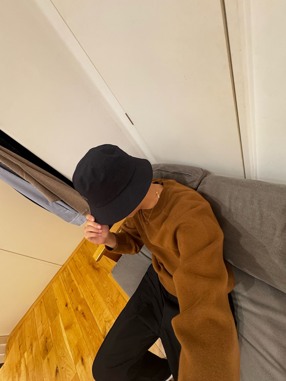 ブラウン系のニット/セーター、ブラック系のその他パンツ、ホワイト系のスニーカーを着用したメンズの秋コーディネートの5枚目の写真