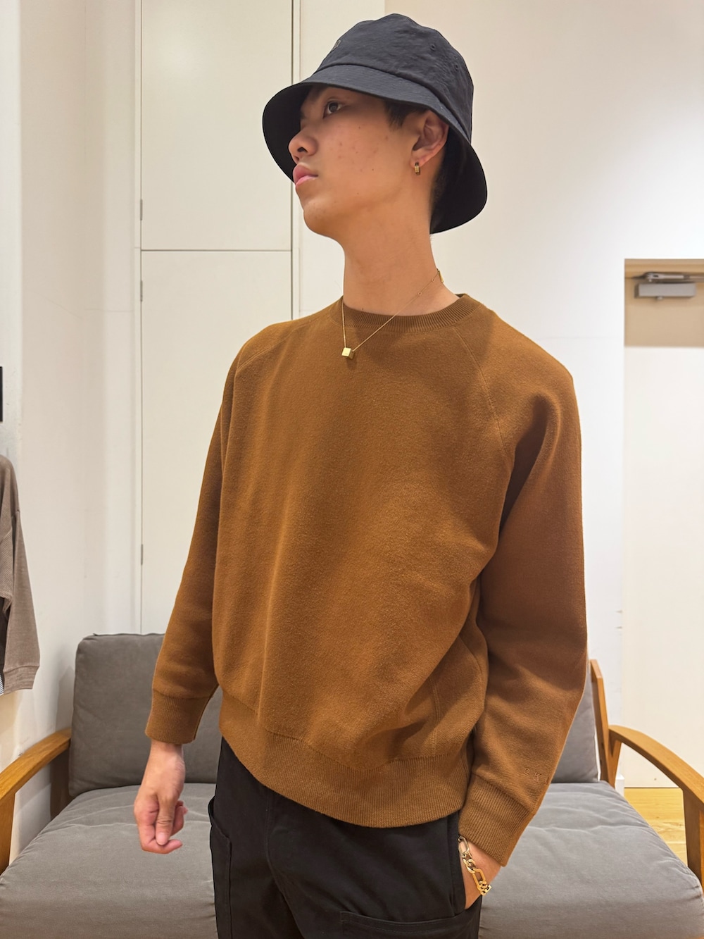 ブラウン系のニット/セーター、ブラック系のその他パンツ、ホワイト系のスニーカーを着用したメンズの秋コーディネートの6枚目の写真