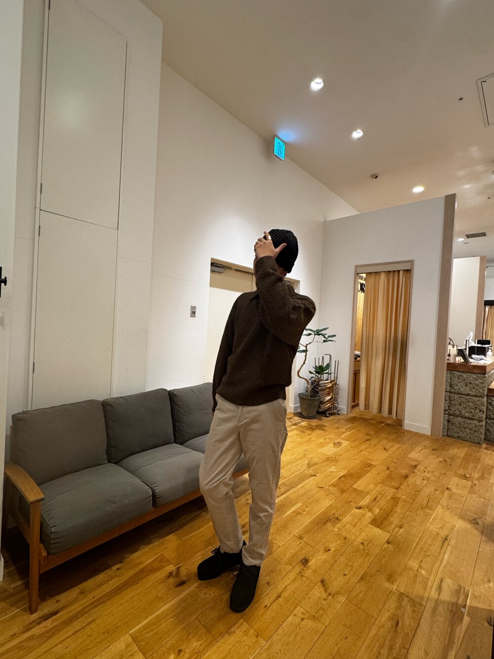 ブラウン系のニット/セーター、ホワイト系のその他パンツ、ブラック系のブーツを着用したメンズの秋コーディネートの4枚目の写真