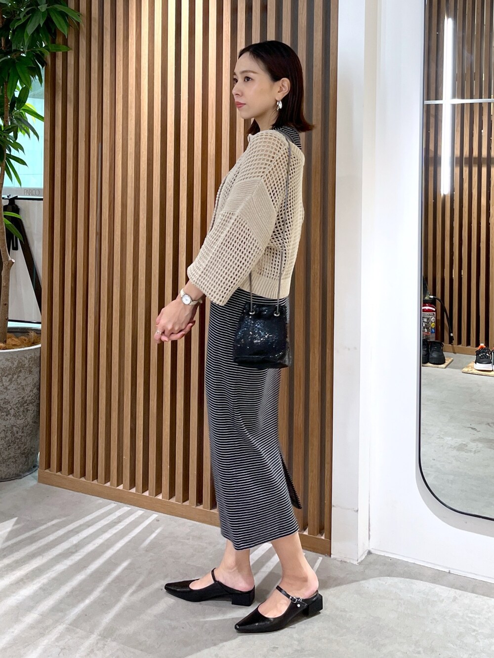 ベージュ系のカーディガン/ボレロ、ブラック系のショルダーバッグ、ブラック系のワンピースを着用したレディースの春コーディネートの4枚目の写真