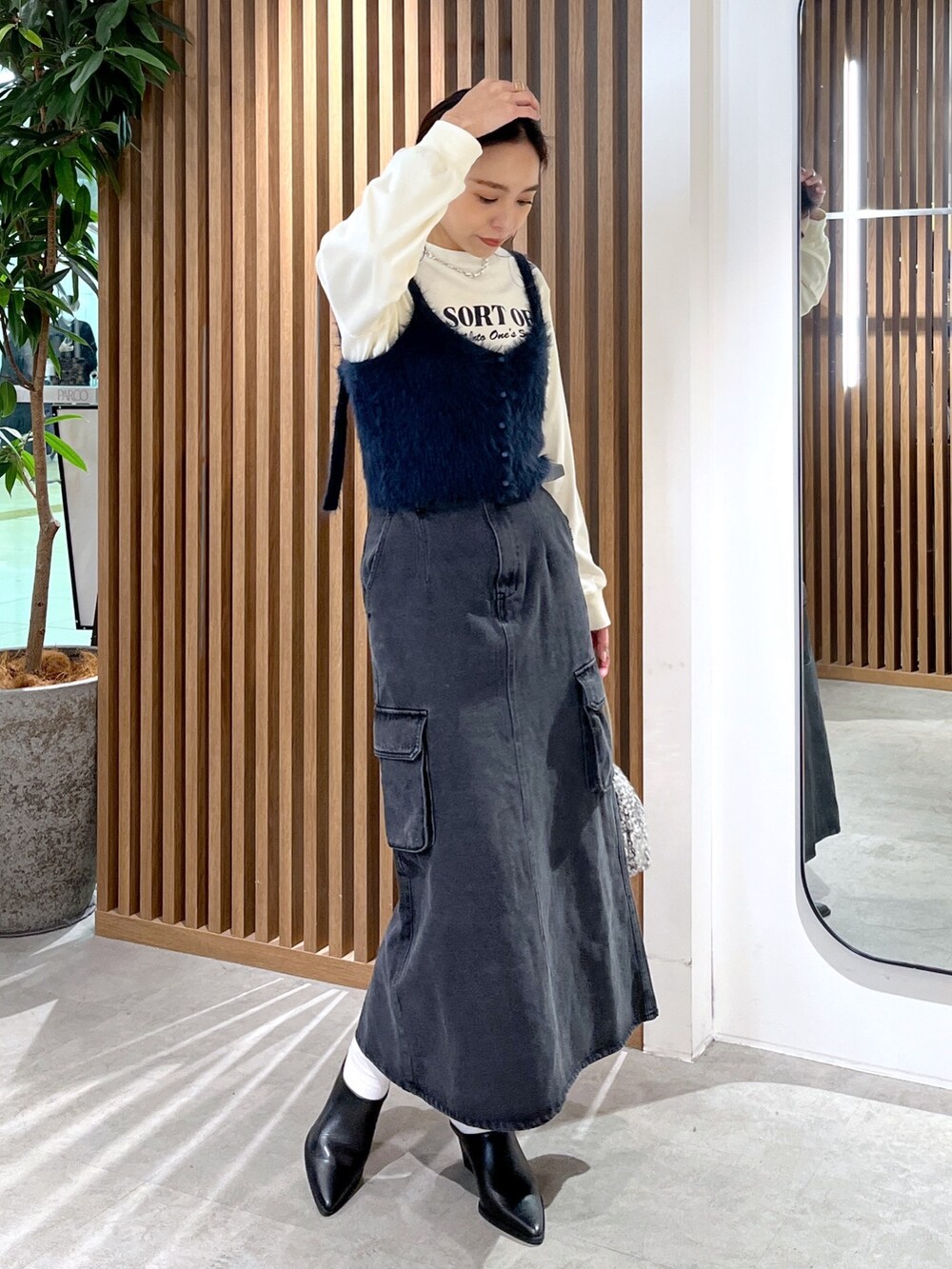 ベージュ系のTシャツ/カットソー、ブルー系のベスト、シルバー系のハンドバッグを着用したレディースの冬コーディネートの3枚目の写真