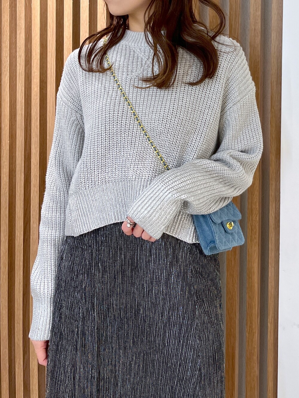 グレー系のニット/セーター、ブルー系のショルダーバッグ、ブラック系のスカートを着用したレディースの冬コーディネートの6枚目の写真