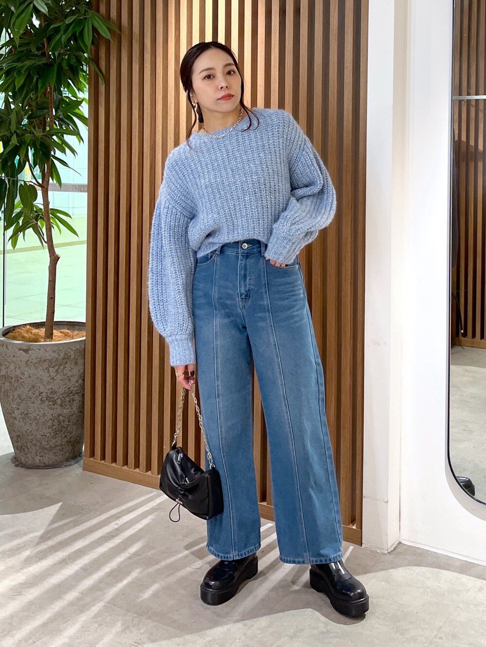 ブルー系のニット/セーター、ブルー系のデニムパンツ、ブラック系のハンドバッグを着用したレディースの冬コーディネートの4枚目の写真