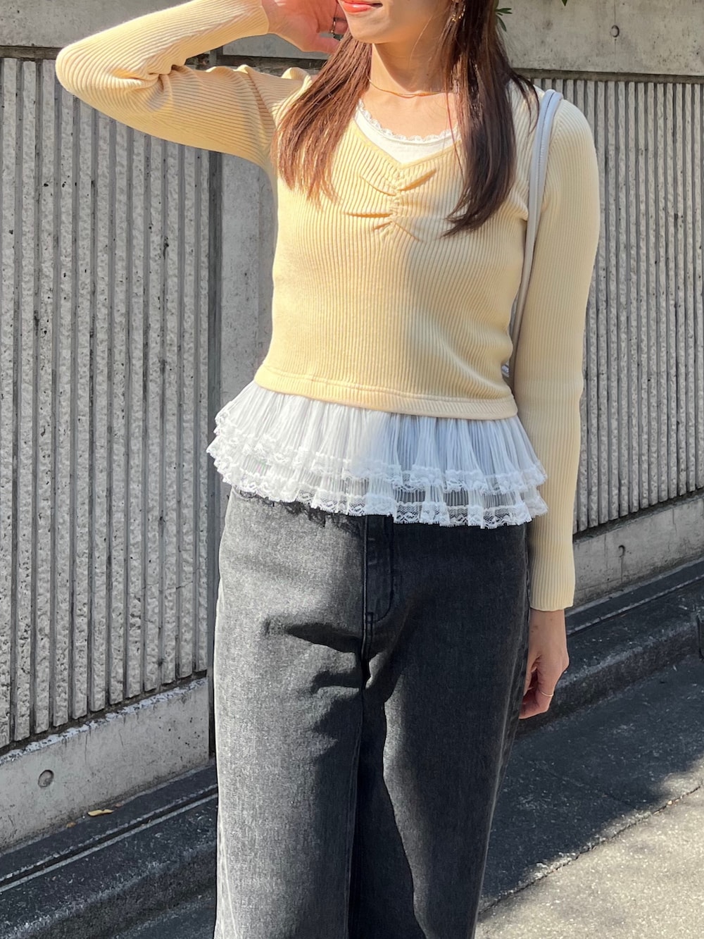 イエロー系のニット/セーター、ブラック系のデニムパンツ、ホワイト系のショルダーバッグを着用したレディースの冬コーディネートの8枚目の写真