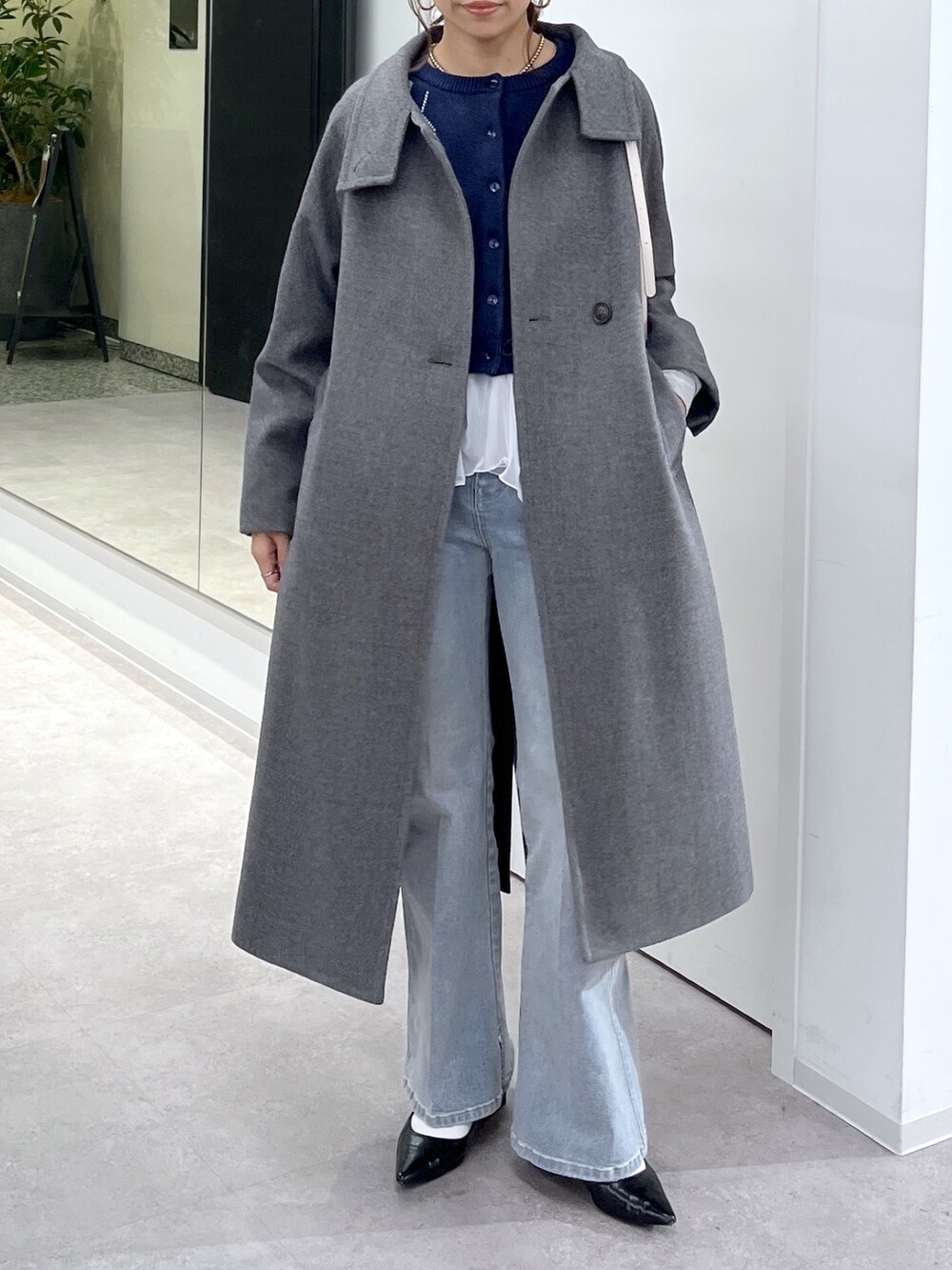 ホワイト系のTシャツ/カットソー、グレー系のステンカラーコート、ブルー系のニット/セーターを着用したレディースの秋コーディネートの7枚目の写真