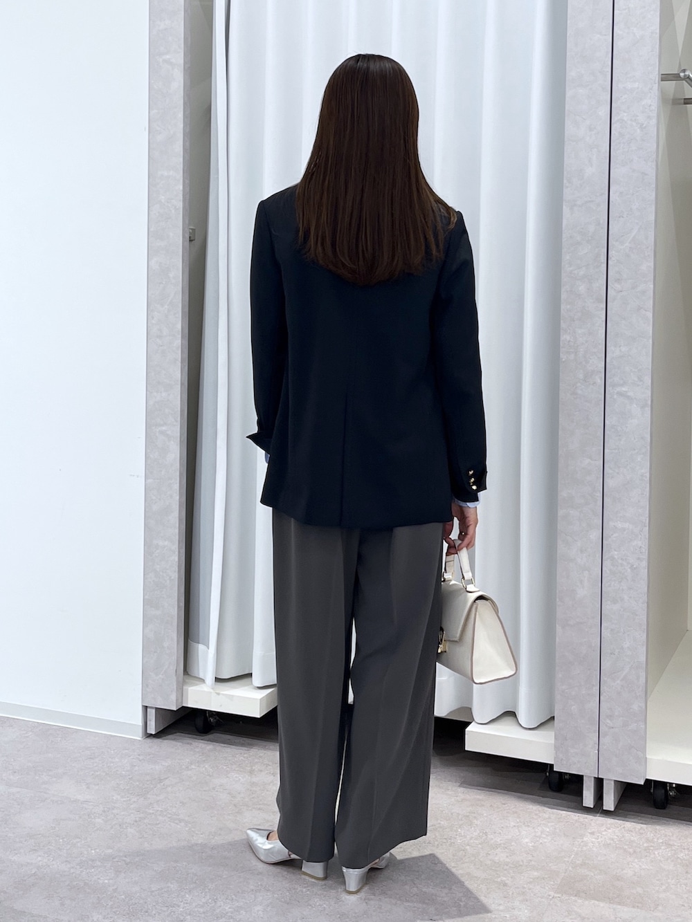 シルバー系のパンプス、グレー系のスラックス、ホワイト系のショルダーバッグを着用したレディースの冬コーディネートの6枚目の写真