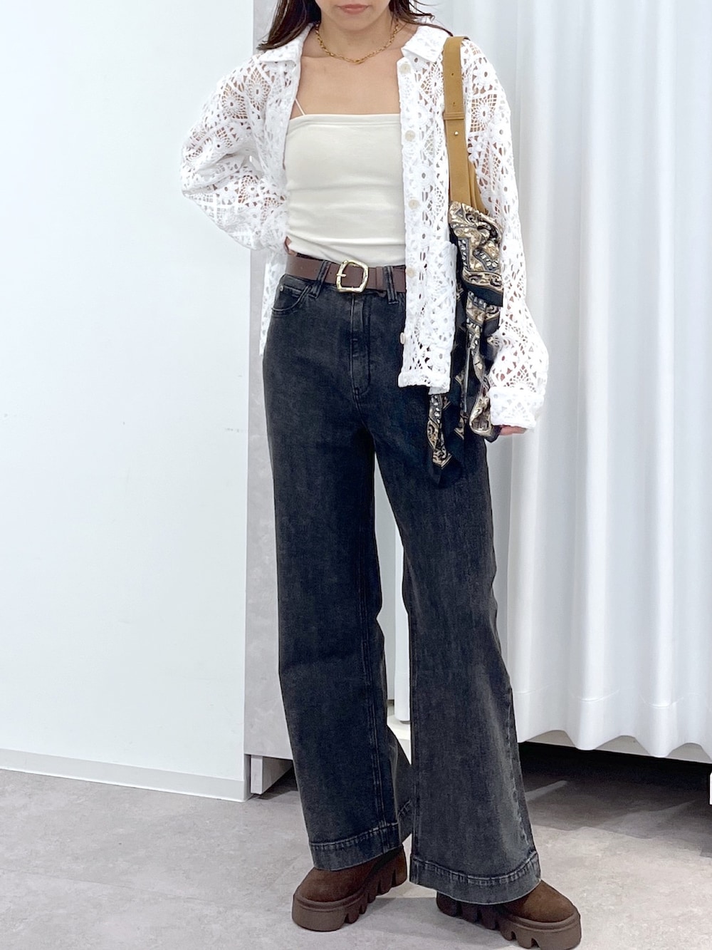 ホワイト系のブルゾン、ブラウン系のショルダーバッグ、ブラック系のデニムパンツを着用したレディースの春コーディネートの4枚目の写真