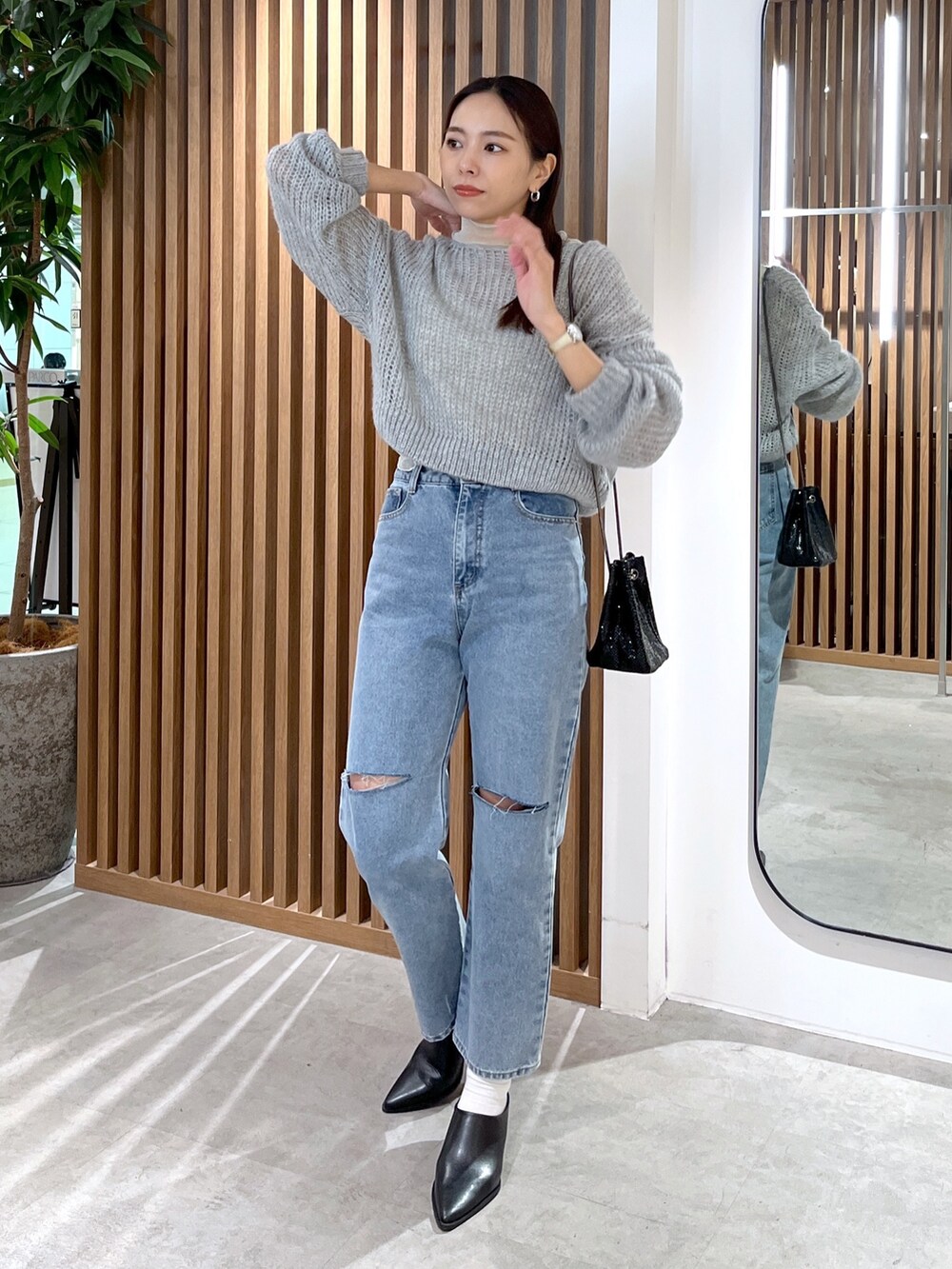 グレー系のニット/セーター、ホワイト系のTシャツ/カットソー、ブルー系のデニムパンツを着用したレディースの冬コーディネートの6枚目の写真