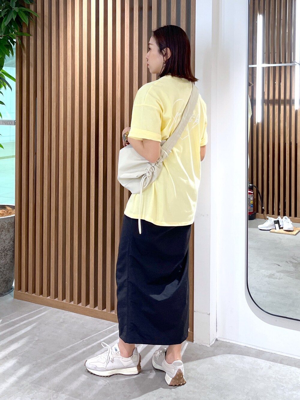 イエロー系のTシャツ/カットソー、ホワイト系のショルダーバッグ、ブラック系のスカートを着用したレディースの春コーディネートの4枚目の写真