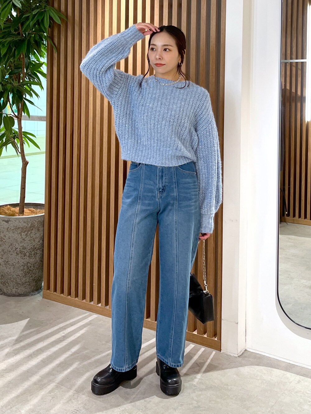 ブルー系のニット/セーター、ブルー系のデニムパンツ、ブラック系のハンドバッグを着用したレディースの冬コーディネートの9枚目の写真