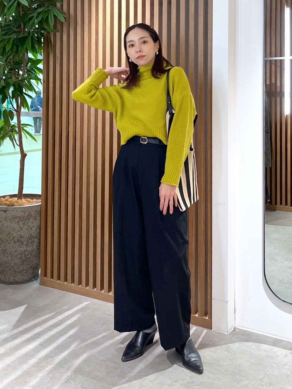 イエロー系のニット/セーター、ブラック系のスラックス、ブラック系のショルダーバッグを着用したレディースの冬コーディネートの7枚目の写真