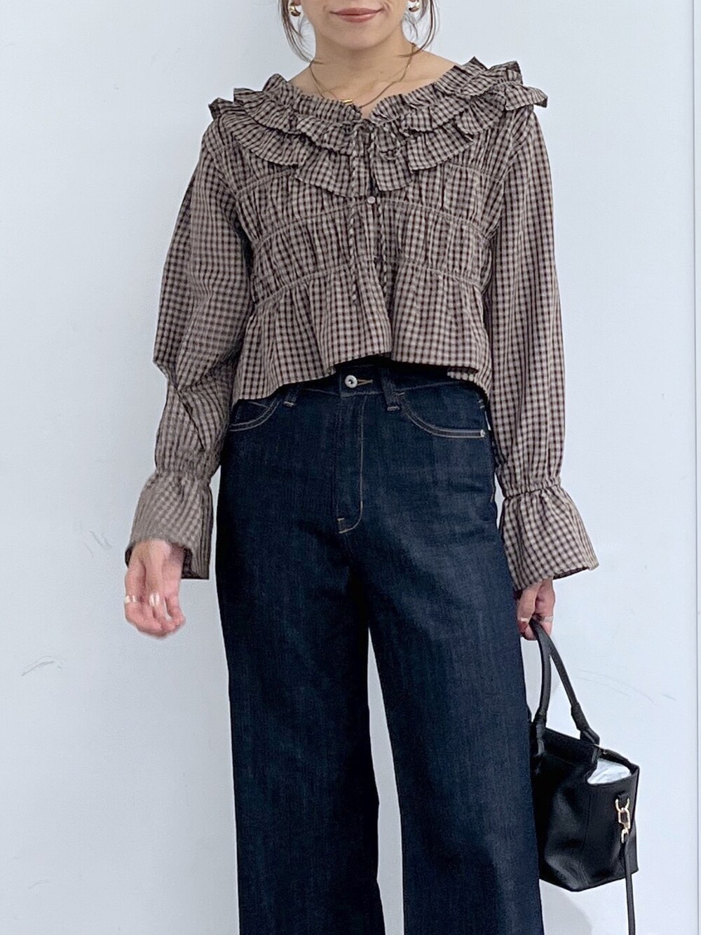 ブルー系のデニムパンツ、ブラック系のハンドバッグ、ブラウン系のシャツ/ブラウスを着用したレディースの秋コーディネートの5枚目の写真