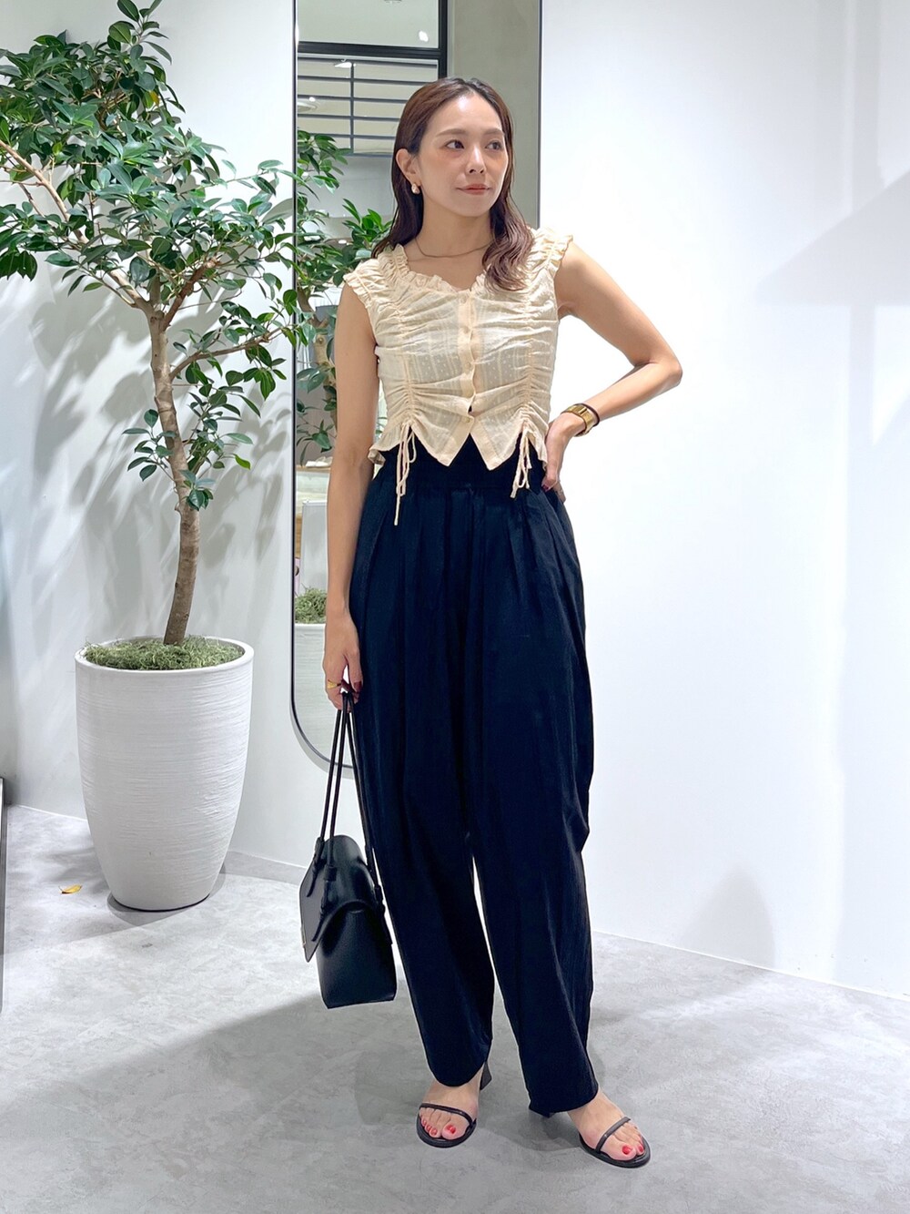 ブラック系のショルダーバッグ、ブラック系のパンツ、イエロー系のシャツ/ブラウスを着用したレディースの夏コーディネートの3枚目の写真