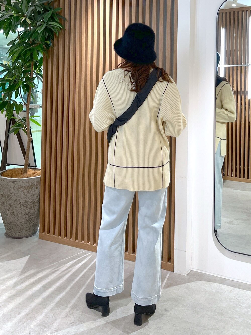 ブラック系のショルダーバッグ、ホワイト系のニット/セーター、ブルー系のデニムパンツを着用したレディースの冬コーディネートの5枚目の写真