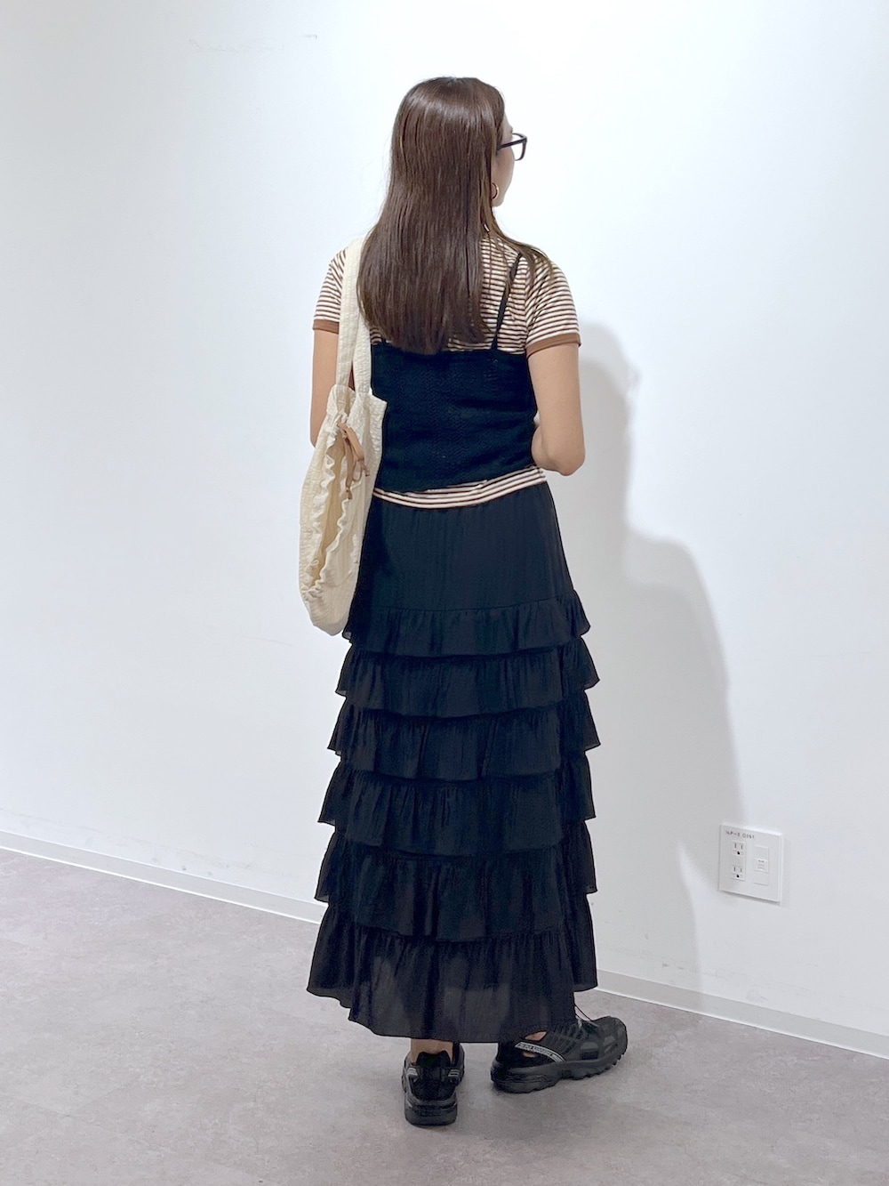 ホワイト系のトートバッグ、ブラック系のスカート、ブラック系のニット/セーターを着用したレディースの夏コーディネートの4枚目の写真