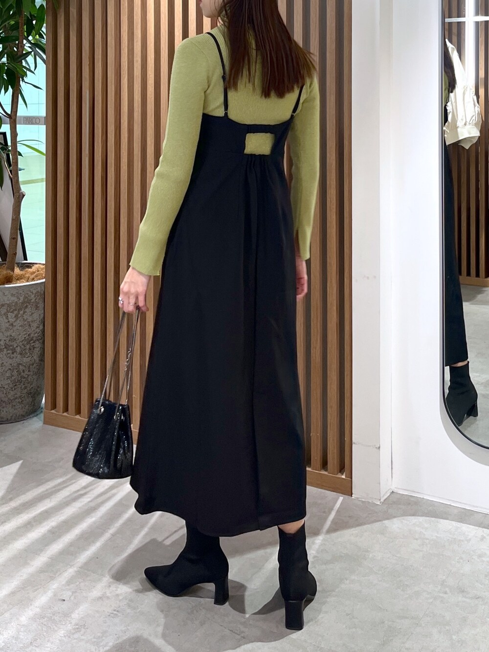 ブラック系のショルダーバッグ、ブラック系のワンピース、グリーン系のニット/セーターを着用したレディースの冬コーディネートの6枚目の写真