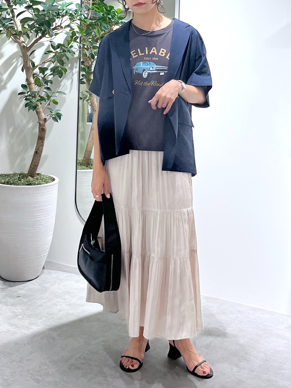 ブルー系のテーラードジャケット、ブラック系のハンドバッグ、ホワイト系のスカートを着用したレディースの夏コーディネートの4枚目の写真