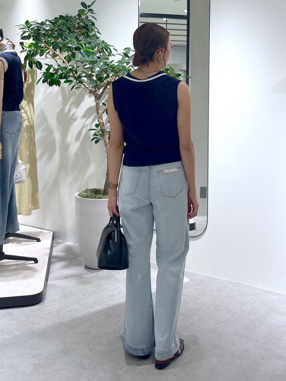 ブルー系のニット/セーター、ブルー系のデニムパンツ、ブラック系のショルダーバッグを着用したレディースの夏コーディネートの5枚目の写真