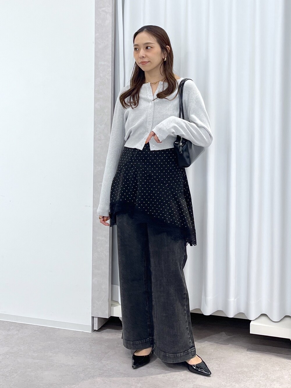 ブラック系のワンピース、ブラック系のデニムパンツ、ブラック系のショルダーバッグを着用したレディースの春コーディネートの8枚目の写真