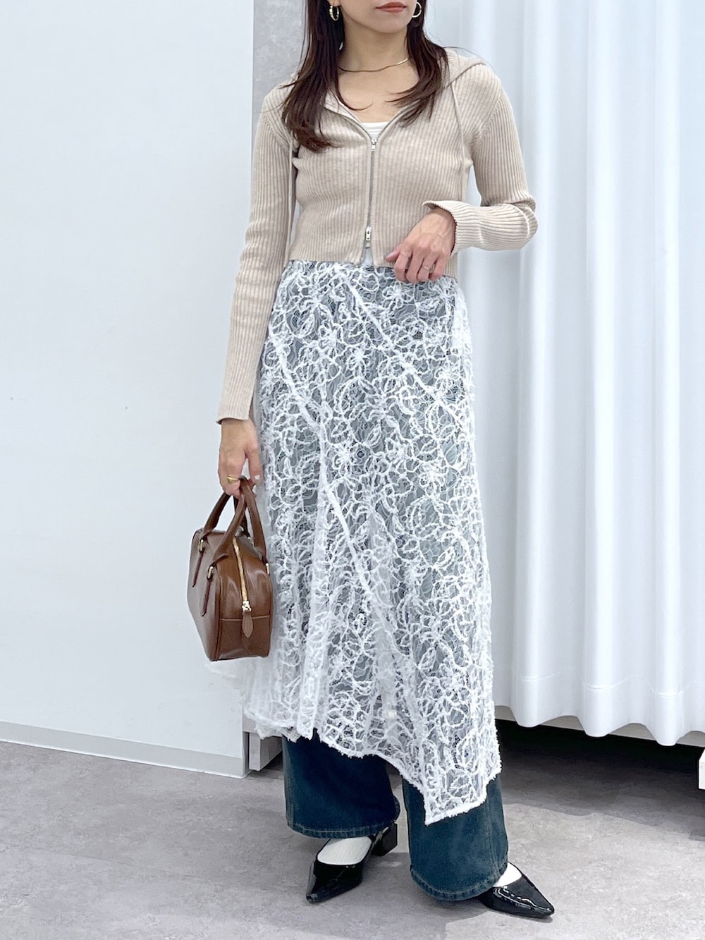 ベージュ系のニット/セーター、ブラウン系のハンドバッグ、ブルー系のデニムパンツを着用したレディースの冬コーディネートの8枚目の写真