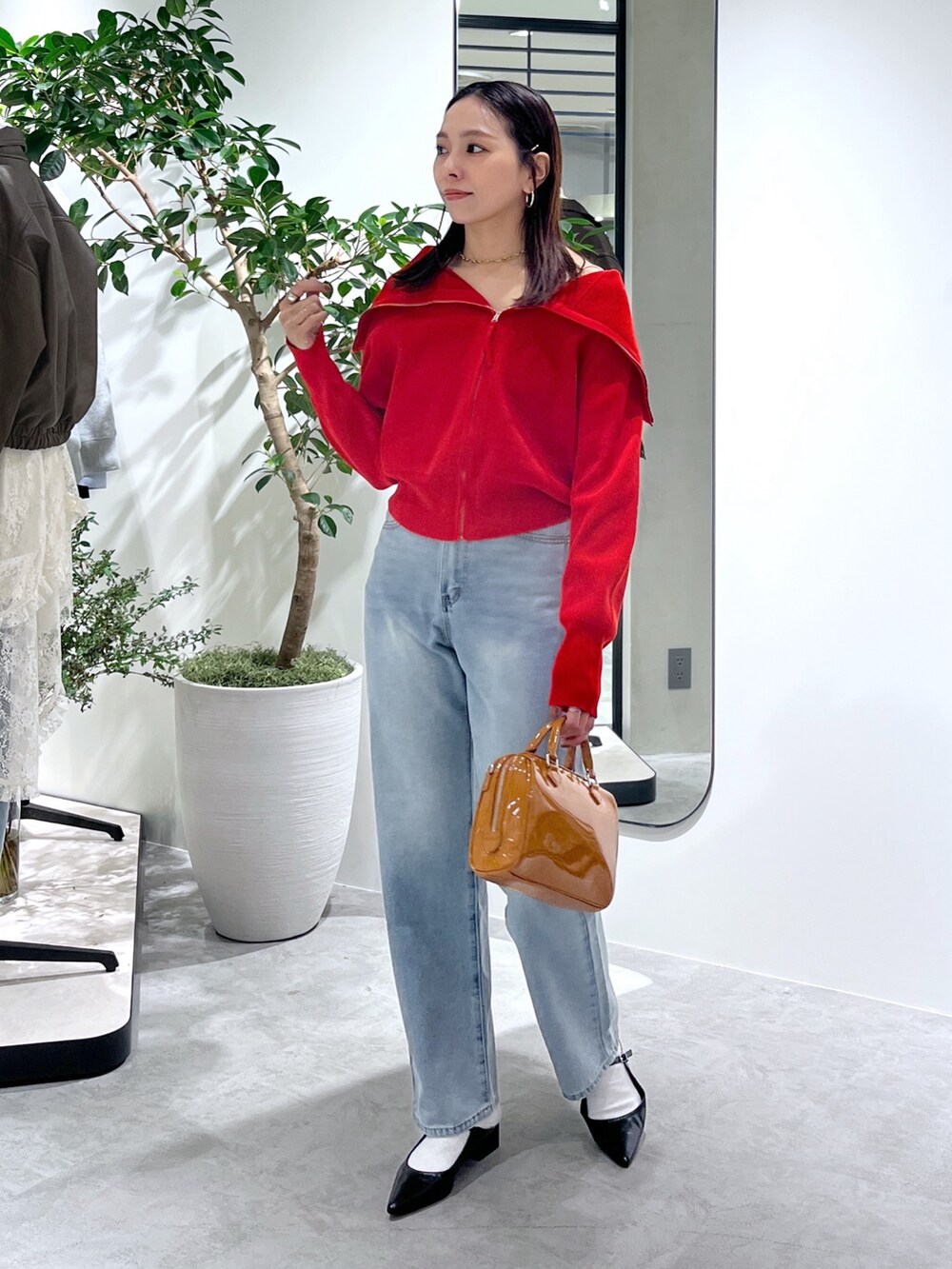 レッド系のニット/セーター、ブルー系のデニムパンツ、ベージュ系のショルダーバッグを着用したレディースの春コーディネートの5枚目の写真