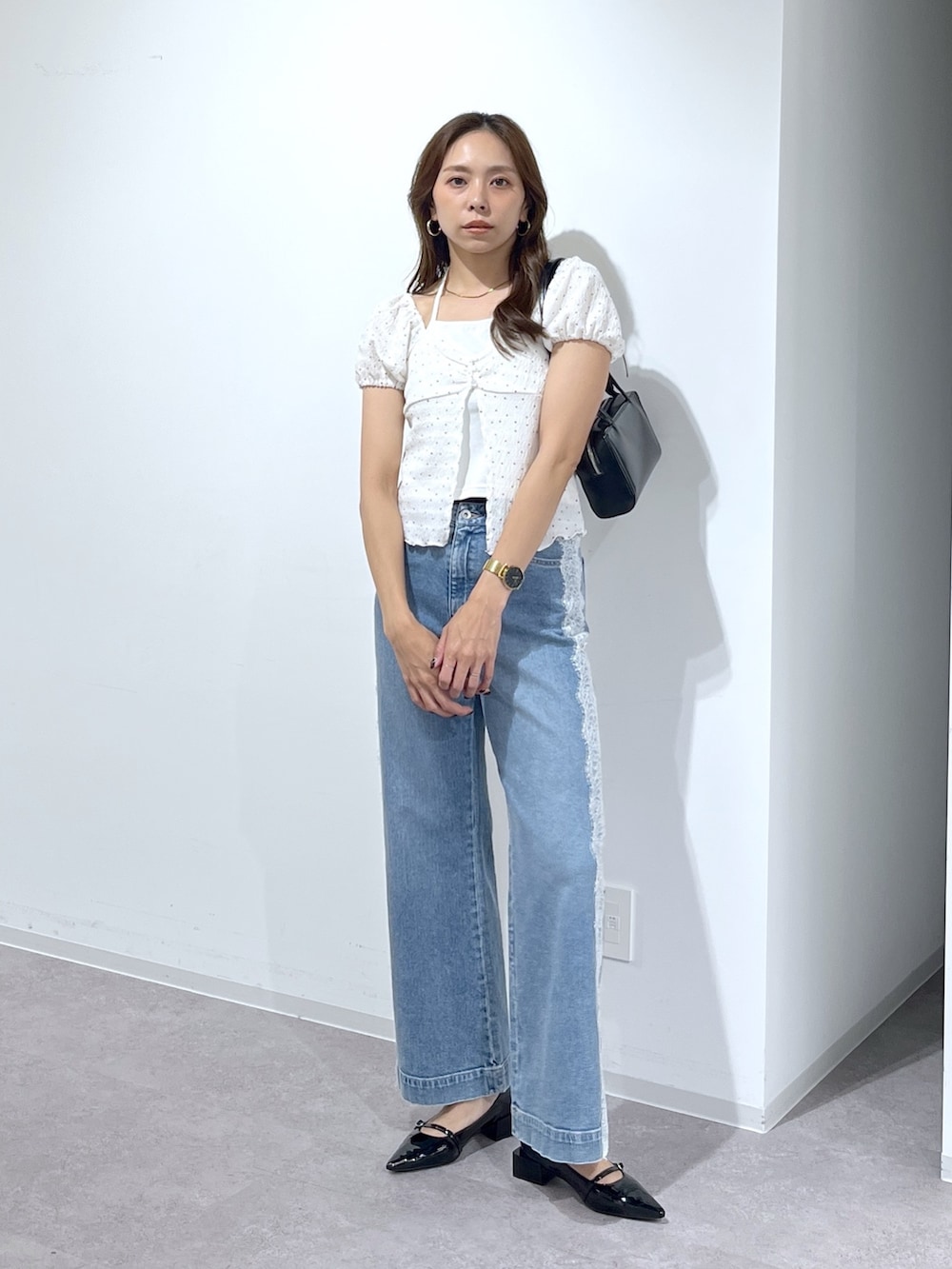 ブラック系のショルダーバッグ、ブラック系のパンプス、ブルー系のデニムパンツを着用したレディースの夏コーディネートの6枚目の写真