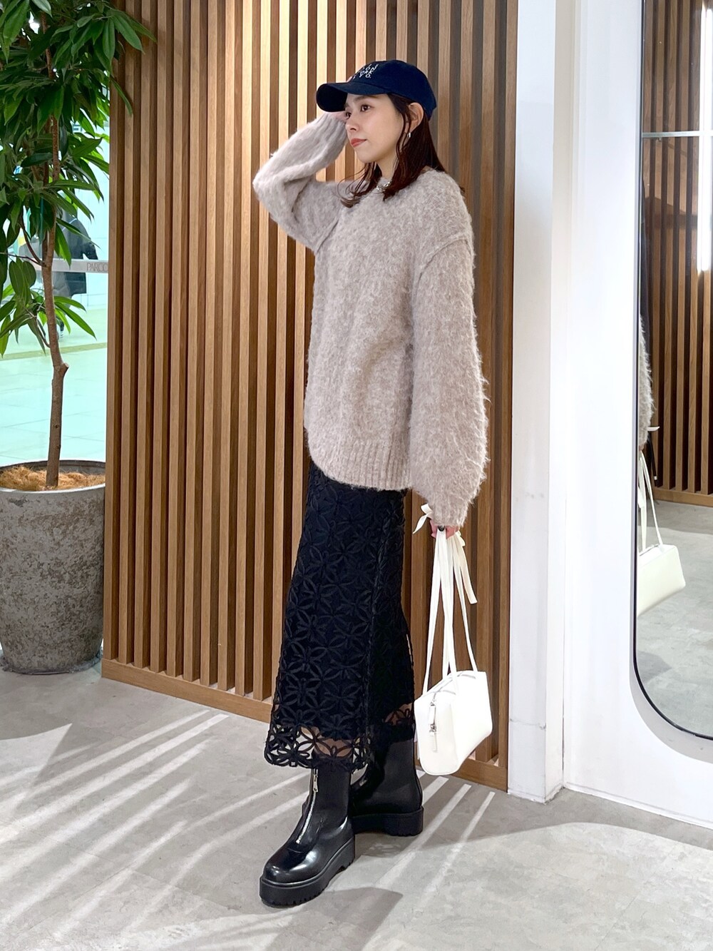 ホワイト系のショルダーバッグ、ベージュ系のニット/セーター、ブラック系のスカートを着用したレディースの冬コーディネートの4枚目の写真