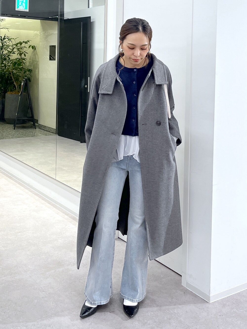 ホワイト系のTシャツ/カットソー、グレー系のステンカラーコート、ブルー系のニット/セーターを着用したレディースの秋コーディネートの10枚目の写真