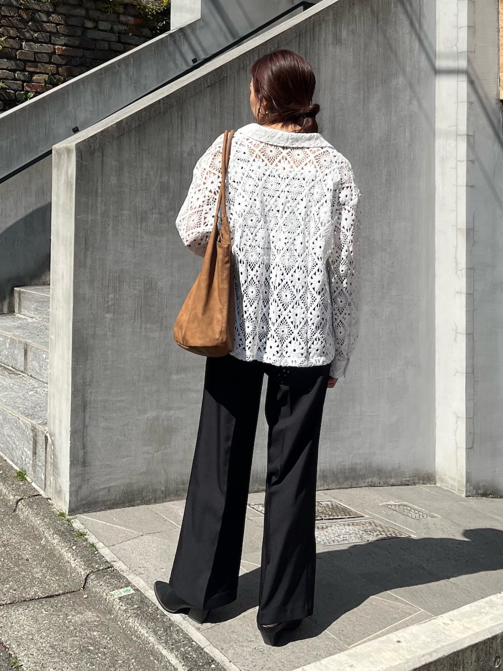 ブラック系のスラックス、ブラウン系のトートバッグ、ホワイト系のブルゾンを着用したレディースの春コーディネートの5枚目の写真