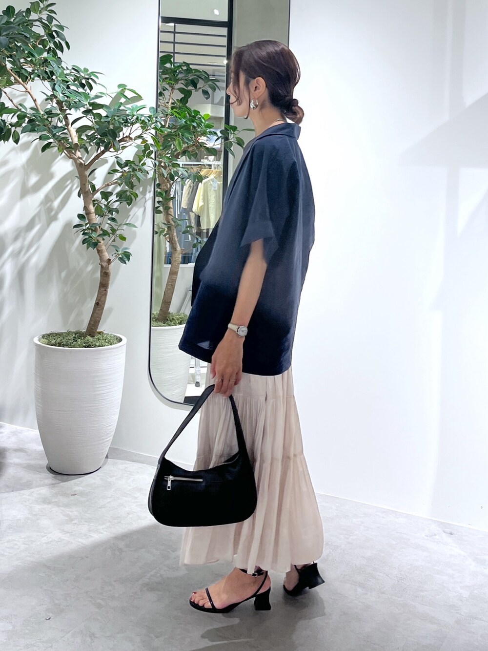 ブルー系のテーラードジャケット、ブラック系のハンドバッグ、ホワイト系のスカートを着用したレディースの夏コーディネートの6枚目の写真