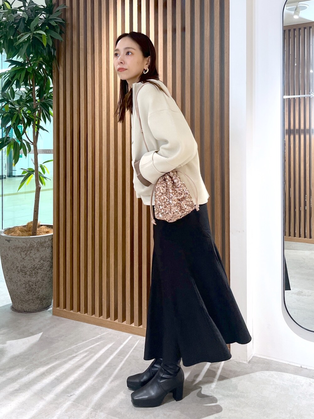 ピンク系のハンドバッグ、ホワイト系のカーディガン/ボレロ、ブラック系のスカートを着用したレディースの秋コーディネートの4枚目の写真