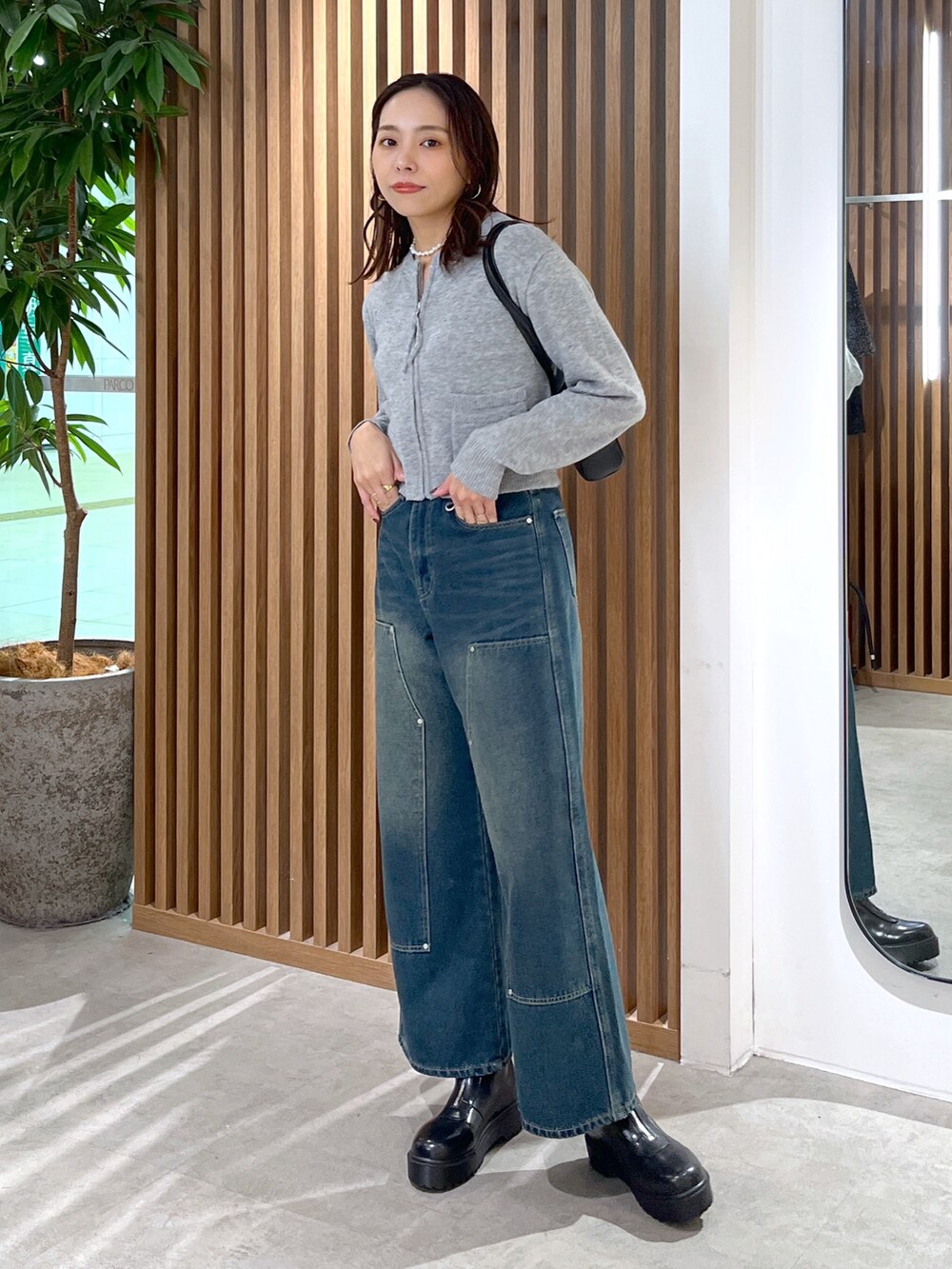 グレー系のワンピース、ブルー系のデニムパンツ、ブラック系のブーツを着用したレディースの冬コーディネートの10枚目の写真