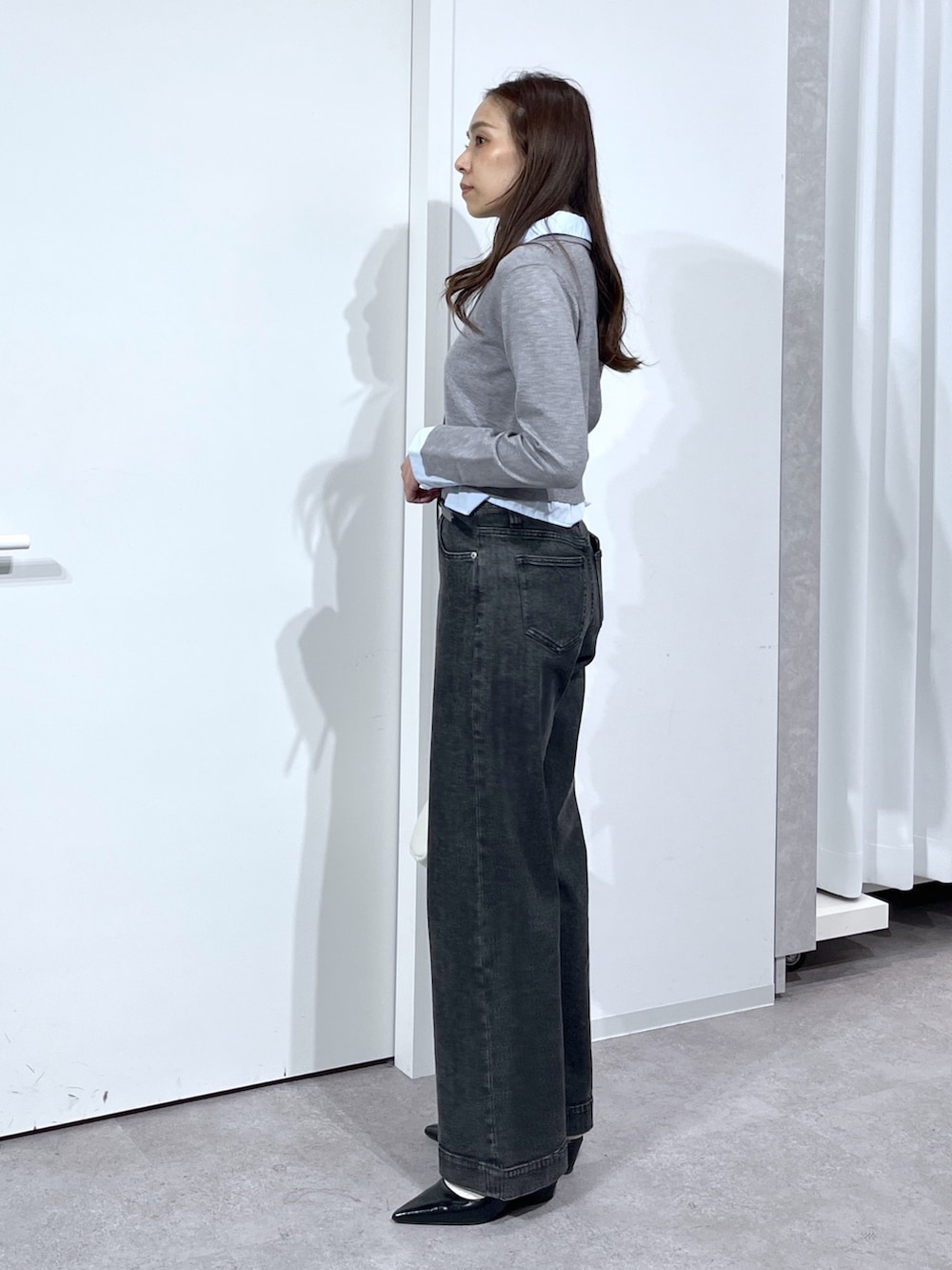 グレー系のニット/セーター、ホワイト系のハンドバッグ、ブラック系のデニムパンツを着用したレディースの春コーディネートの8枚目の写真