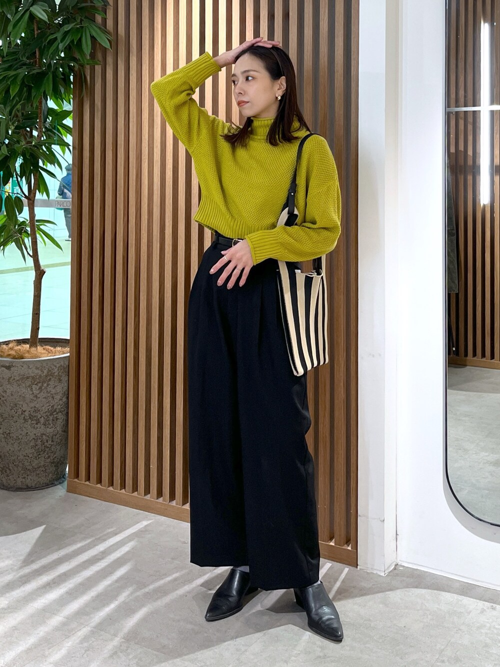 イエロー系のニット/セーター、ブラック系のスラックス、ブラック系のショルダーバッグを着用したレディースの冬コーディネートの9枚目の写真