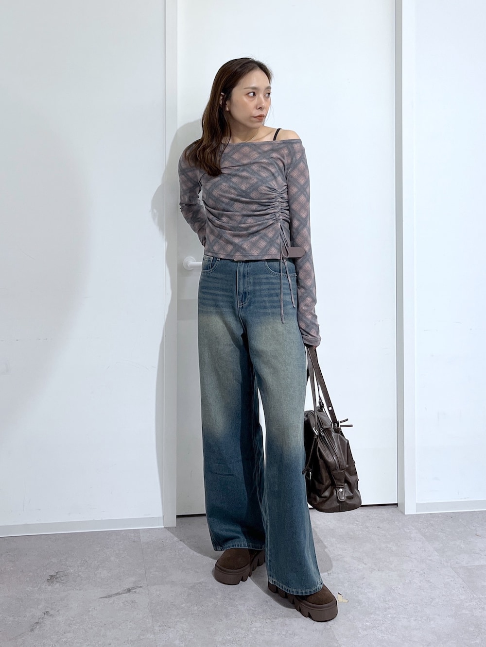 ブラウン系のショルダーバッグ、ブラウン系のTシャツ/カットソー、ブルー系のデニムパンツを着用したレディースの夏コーディネートの2枚目の写真