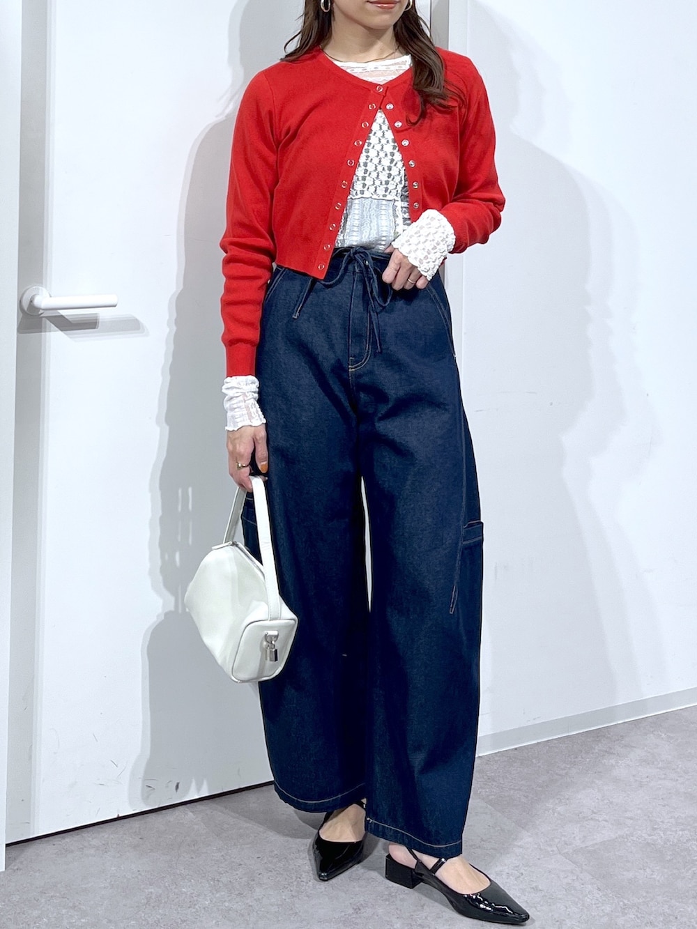 ホワイト系のTシャツ/カットソー、レッド系のニット/セーター、ブルー系のデニムパンツを着用したレディースの春コーディネートの3枚目の写真
