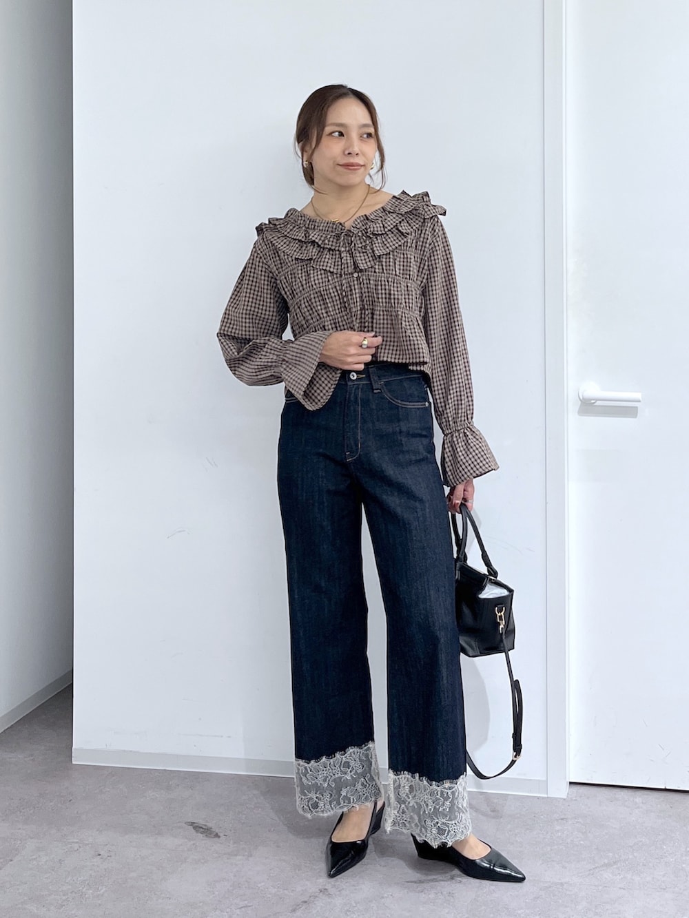 ブルー系のデニムパンツ、ブラック系のハンドバッグ、ブラウン系のシャツ/ブラウスを着用したレディースの秋コーディネートの2枚目の写真