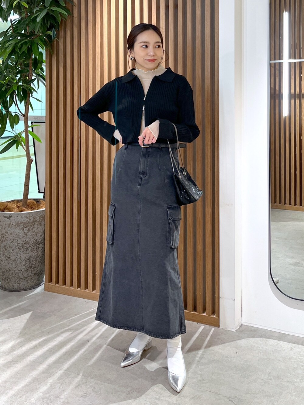 ブラック系のニット/セーター、ホワイト系のTシャツ/カットソー、ブラック系のショルダーバッグを着用したレディースの冬コーディネートの3枚目の写真