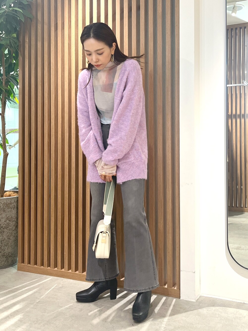 パープル系のカーディガン/ボレロ、ホワイト系のショルダーバッグ、ブラック系のデニムパンツを着用したレディースの秋コーディネートの2枚目の写真