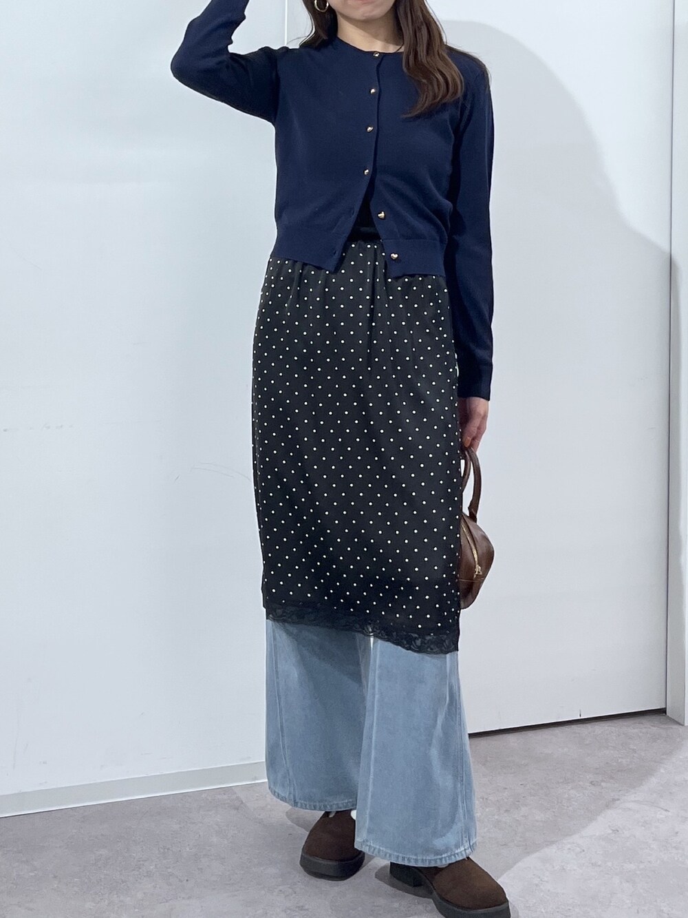 ブルー系のデニムパンツ、ブラウン系のハンドバッグ、ブラック系のスカートを着用したレディースの冬コーディネートの6枚目の写真