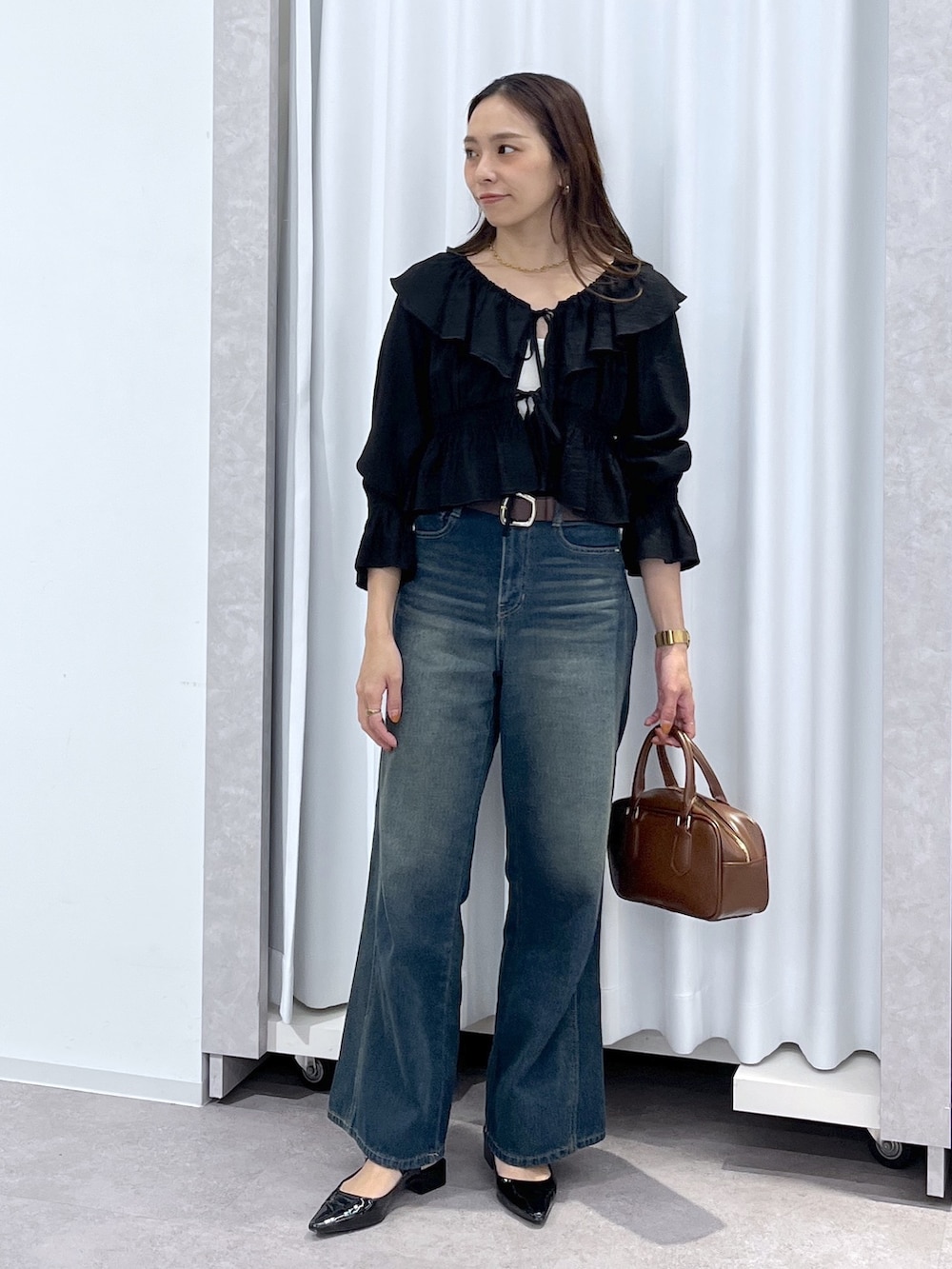 ブラック系のシャツ/ブラウス、ブルー系のデニムパンツ、ブラウン系のハンドバッグを着用したレディースの春コーディネートの7枚目の写真