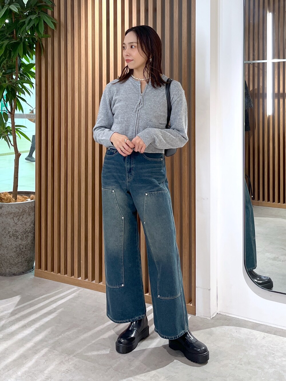 グレー系のワンピース、ブルー系のデニムパンツ、ブラック系のブーツを着用したレディースの冬コーディネートの8枚目の写真