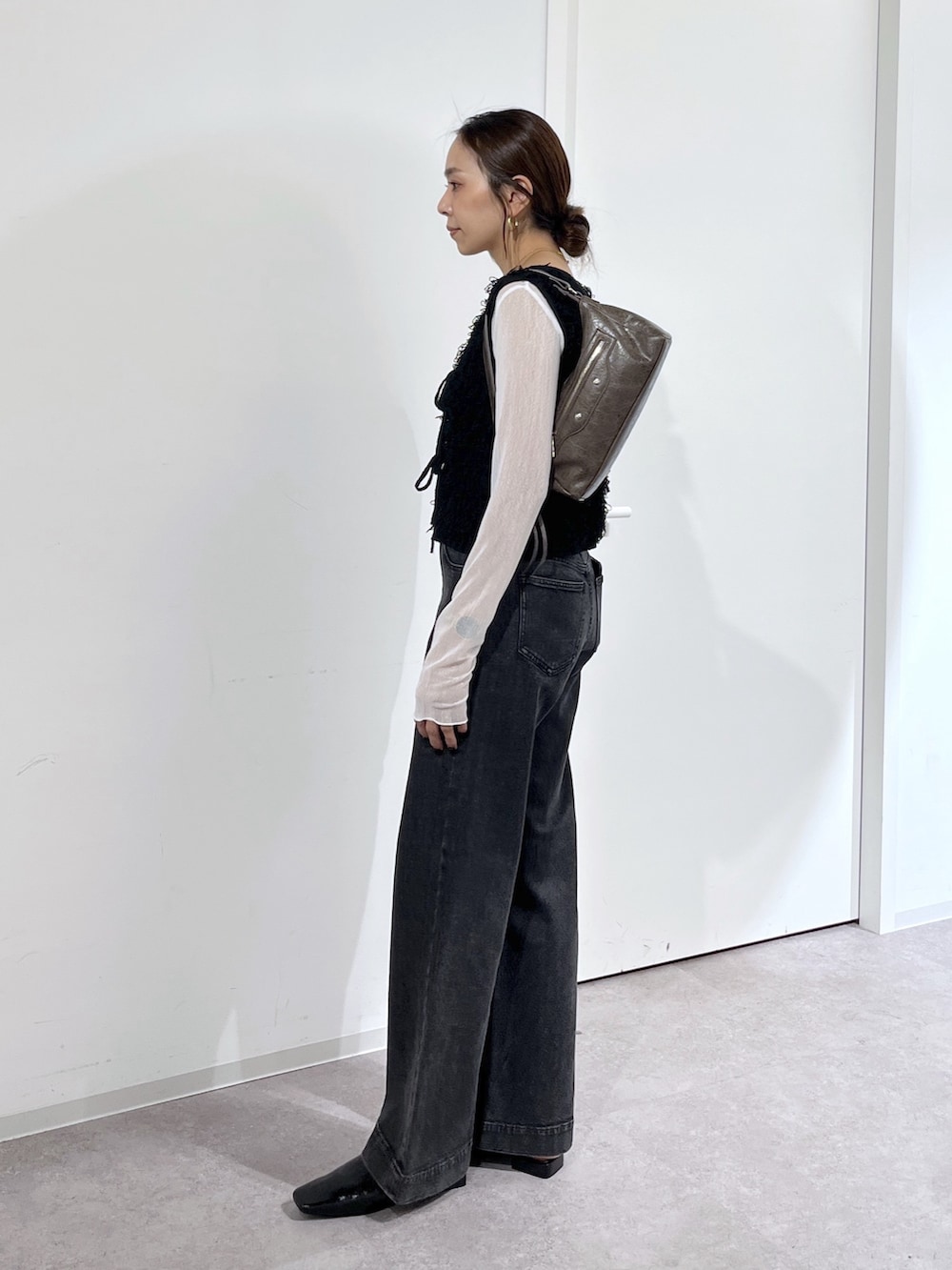 ブラウン系のショルダーバッグ、ブラック系のニット/セーター、ホワイト系のTシャツ/カットソーを着用したレディースの夏コーディネートの4枚目の写真