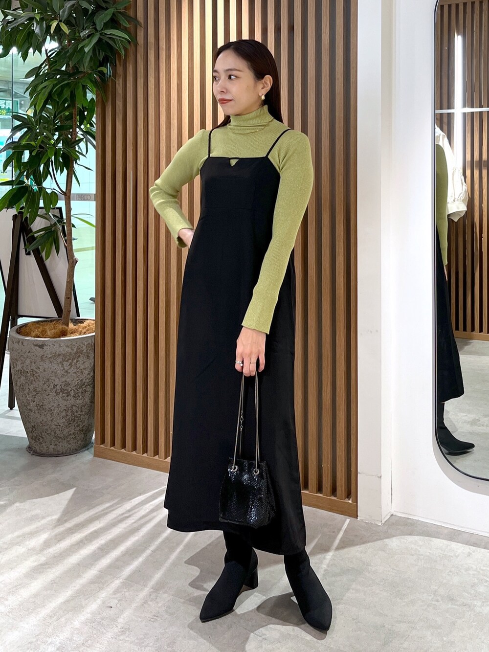 ブラック系のショルダーバッグ、ブラック系のワンピース、グリーン系のニット/セーターを着用したレディースの冬コーディネートの8枚目の写真