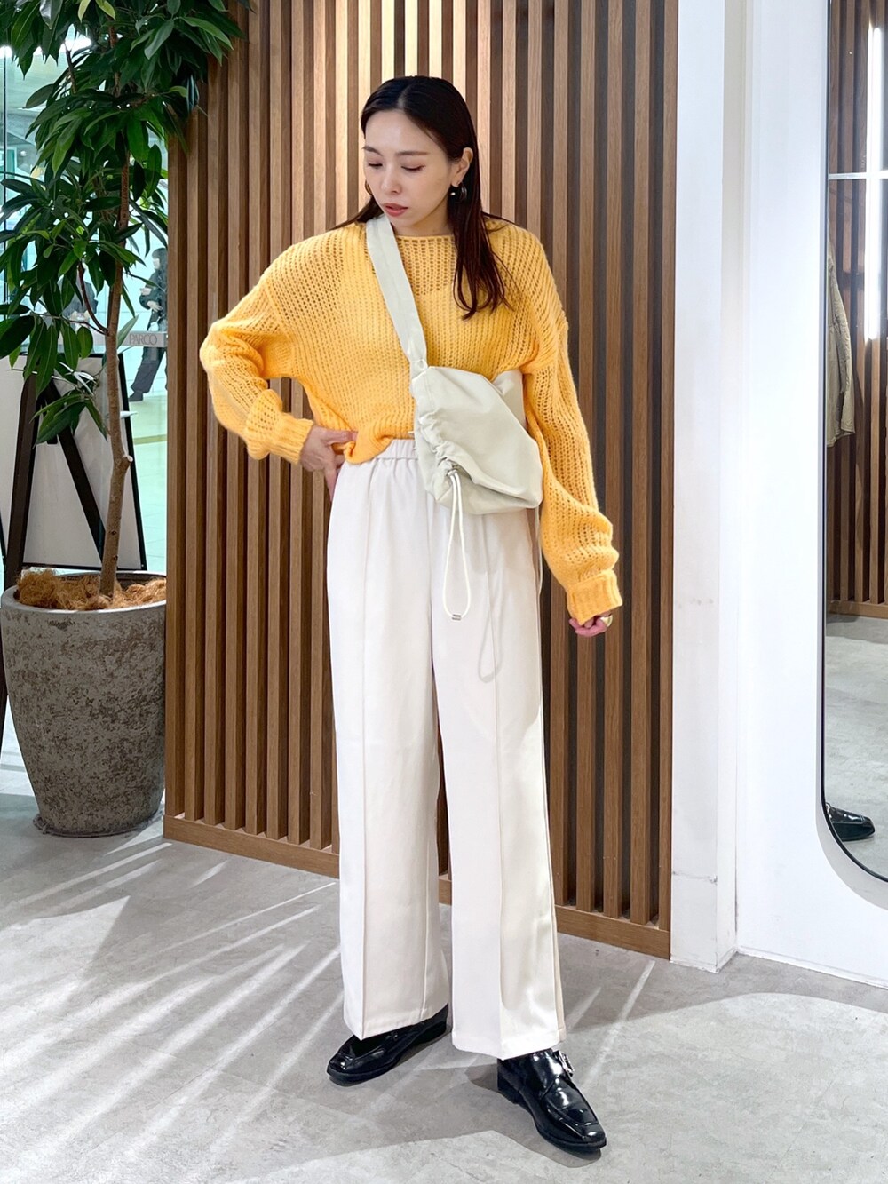 ホワイト系のショルダーバッグ、オレンジ系のニット/セーター、ホワイト系のその他パンツを着用したレディースの冬コーディネートの2枚目の写真