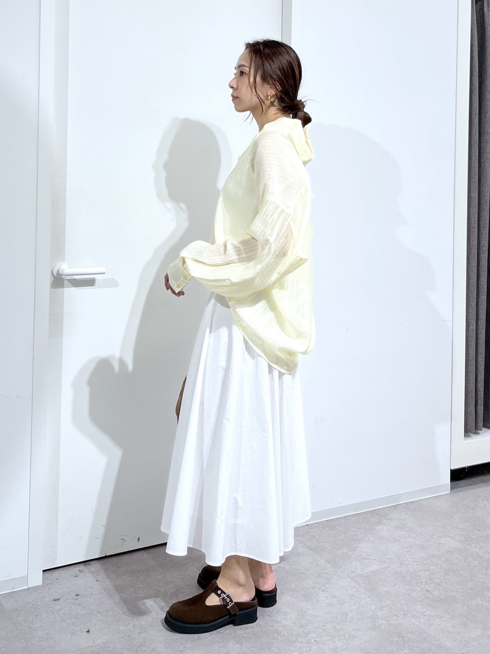 ホワイト系のニット/セーター、イエロー系のシャツ/ブラウス、ホワイト系のスカートを着用したレディースの春コーディネートの8枚目の写真