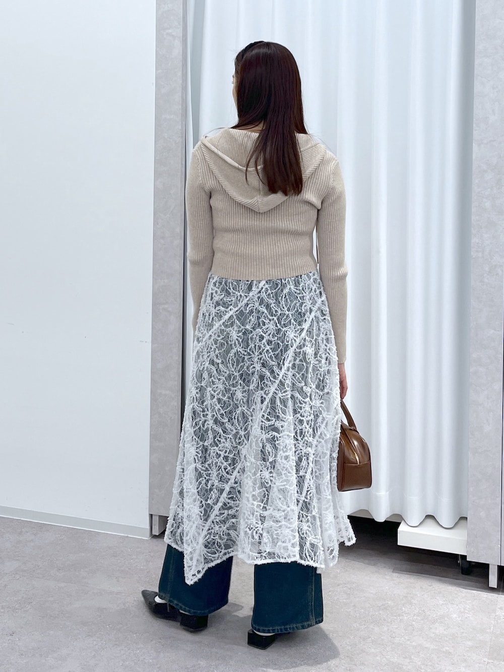 ベージュ系のニット/セーター、ブラウン系のハンドバッグ、ブルー系のデニムパンツを着用したレディースの冬コーディネートの6枚目の写真