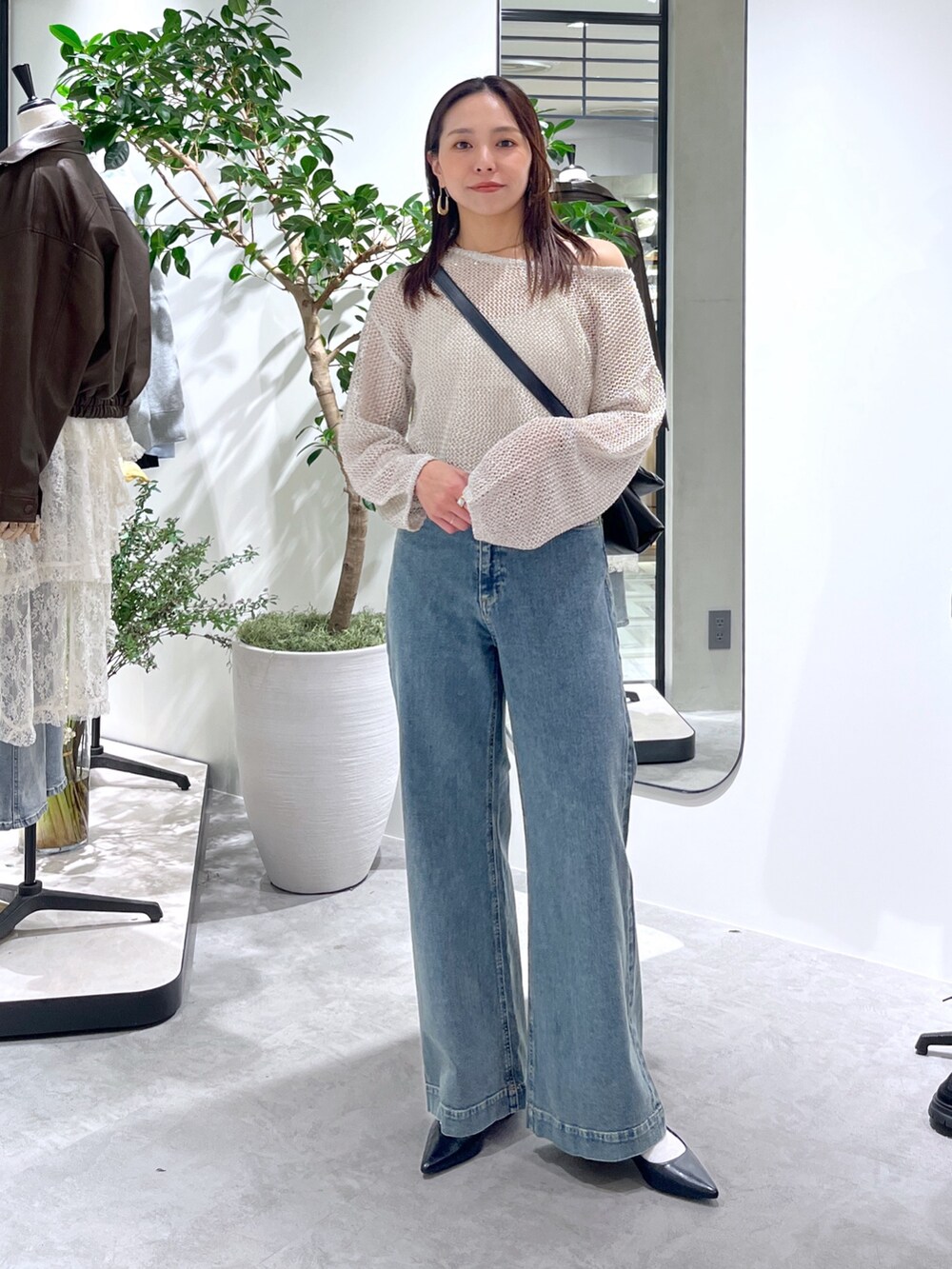 ホワイト系のニット/セーター、ホワイト系のキャミソール、ブラック系のショルダーバッグを着用したレディースの春コーディネートの2枚目の写真