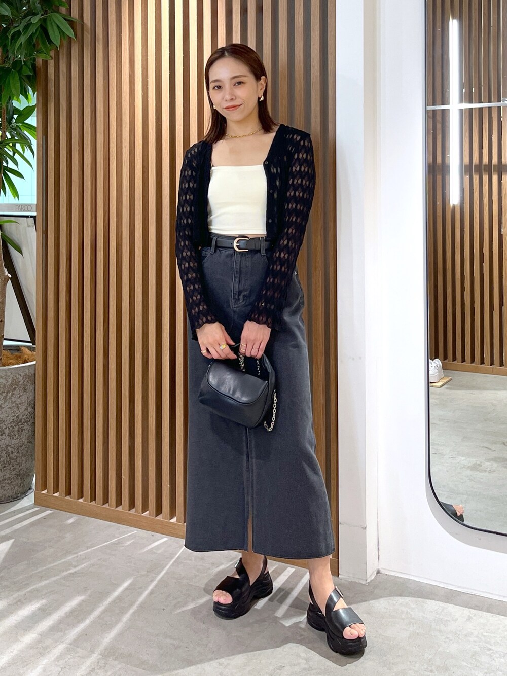 ブラック系のサンダル、ブラック系のショルダーバッグ、ホワイト系のキャミソールを着用したレディースの夏コーディネートの3枚目の写真