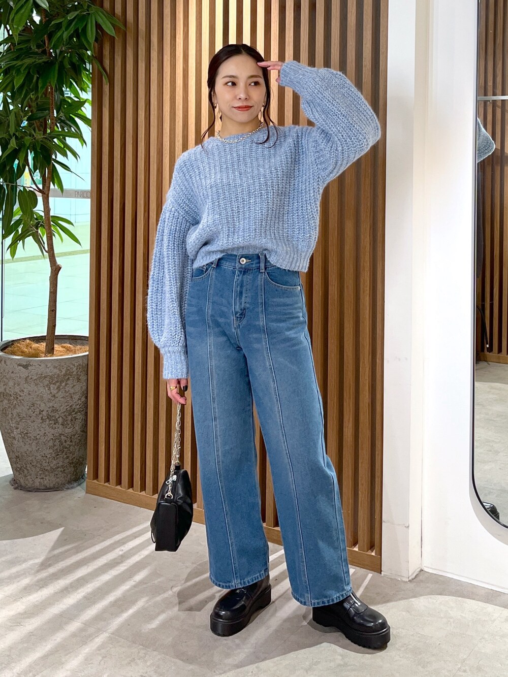 ブルー系のニット/セーター、ブルー系のデニムパンツ、ブラック系のハンドバッグを着用したレディースの冬コーディネートの3枚目の写真